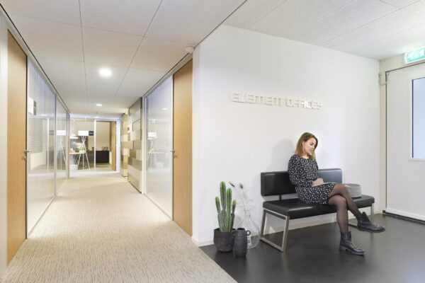 Vrouw zit te wachten in de wachtruimte van Element Offices in de Middenburcht.