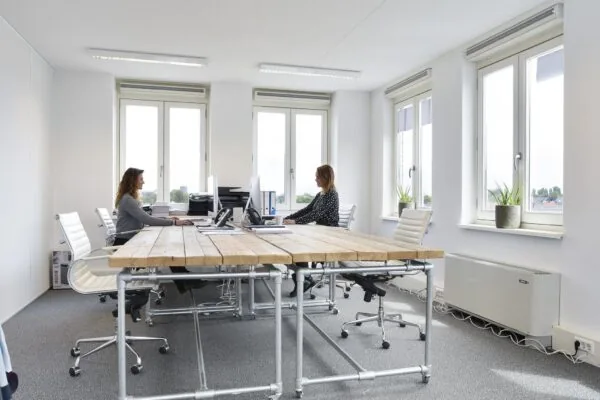 Twee vrouwen werken tegenover elkaar aan bureaus in een modern en licht kantoor aan de Middenburcht.