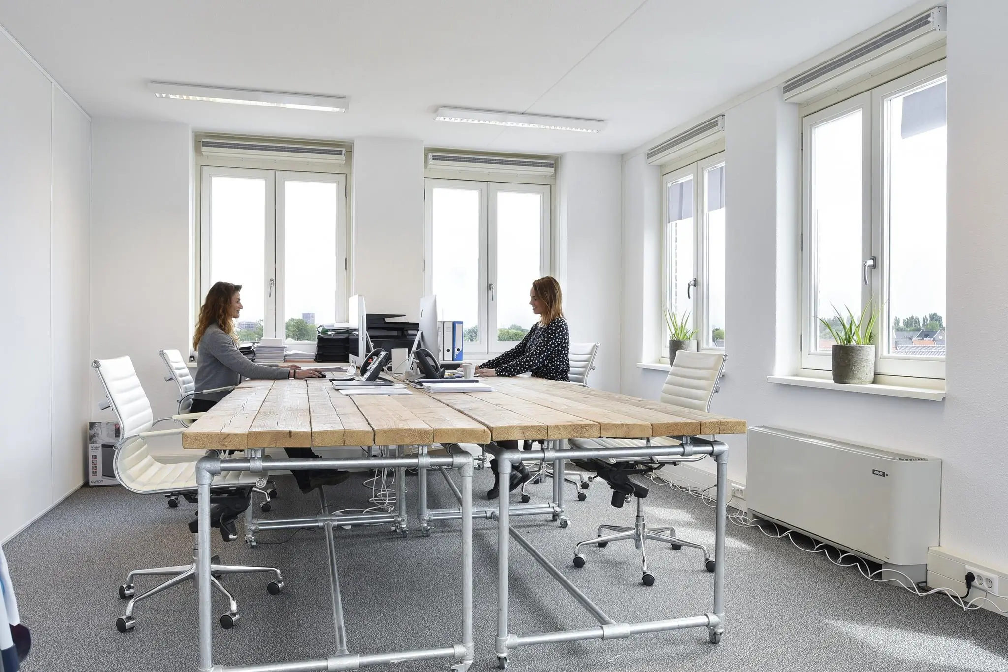 Twee vrouwen werken tegenover elkaar aan bureaus in een modern en licht kantoor aan de Middenburcht.