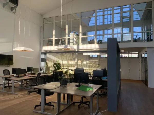 Modern kantoorinterieur aan het Gedempt Hamerkanaal met grote ramen, bureaus en computers in een open werkruimte.