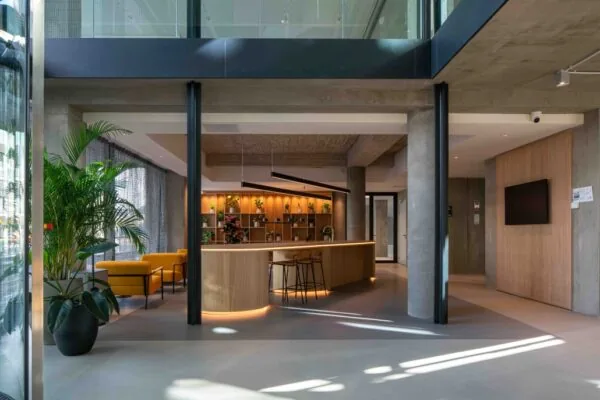 Moderne en sfeervolle ontvangst- of lobbyruimte aan de Catharijnesingel met een houten balie, plantenwand en gele zitbanken.