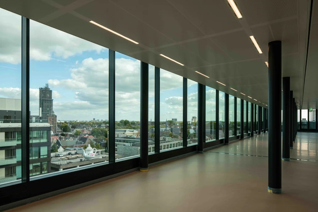 Uitzicht vanaf een moderne gang met glazen wand over de Catharijnesingel en de stad Utrecht.
