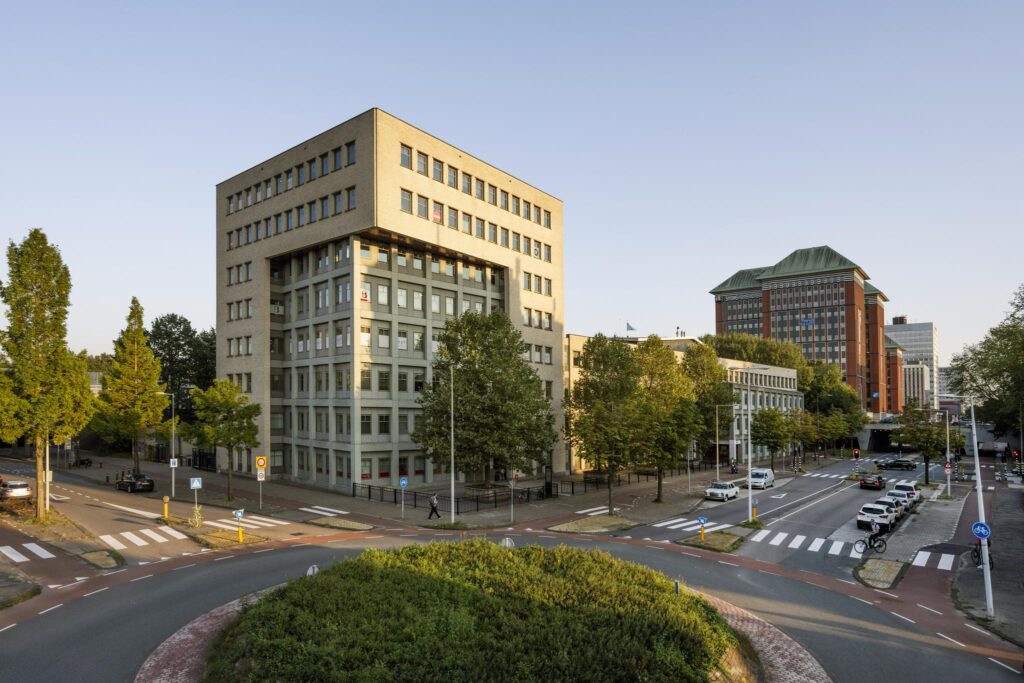 Kantoorgebouw aan de Derkinderenstraat in Amsterdam met omliggende wegen, voetpaden en groenstroken.