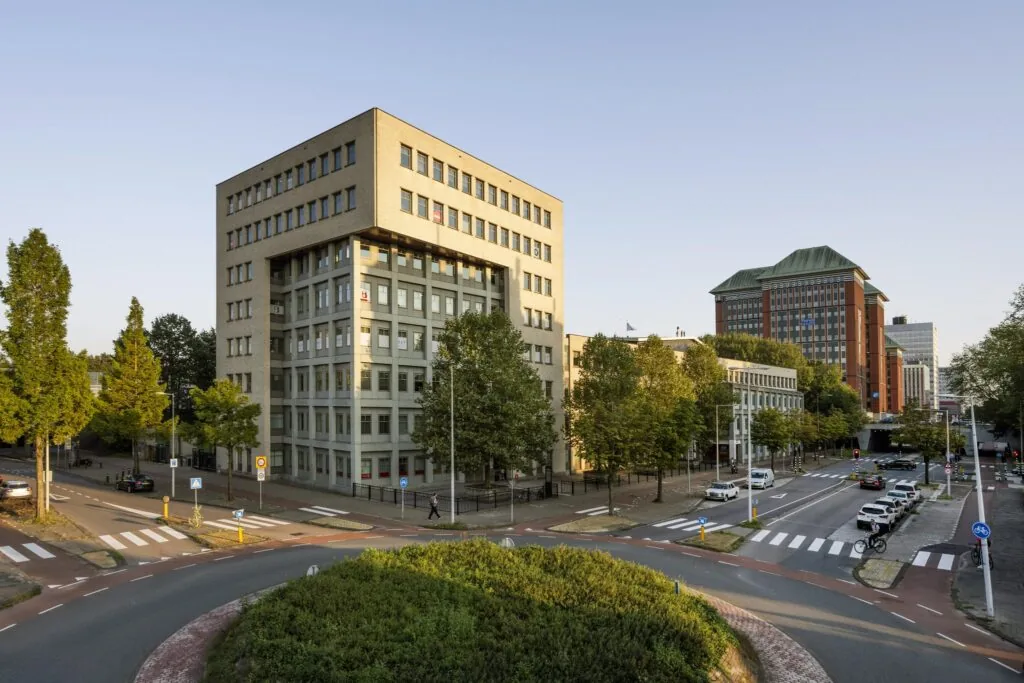 Kantoorgebouw aan de Derkinderenstraat in Amsterdam met omliggende wegen, voetpaden en groenstroken.