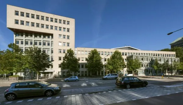 Modern kantoorgebouw aan de Derkinderenstraat in Amsterdam met meerdere verdiepingen en bomen langs de straat.