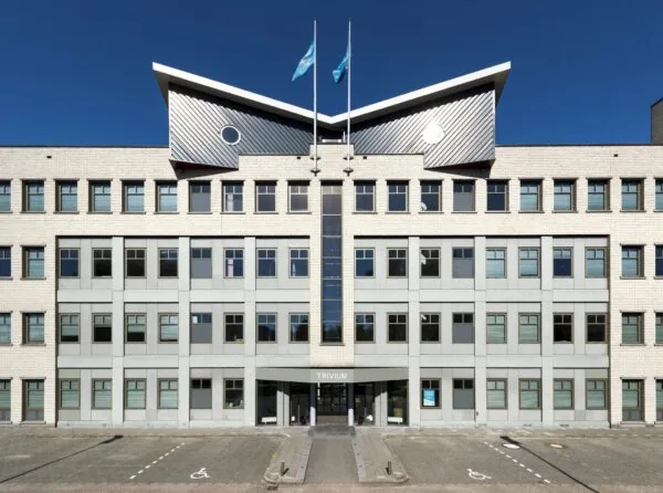 Vooraanzicht van het kantoorgebouw Trivium aan de Derkinderenstraat met symmetrische gevel en twee vlaggen op het dak.