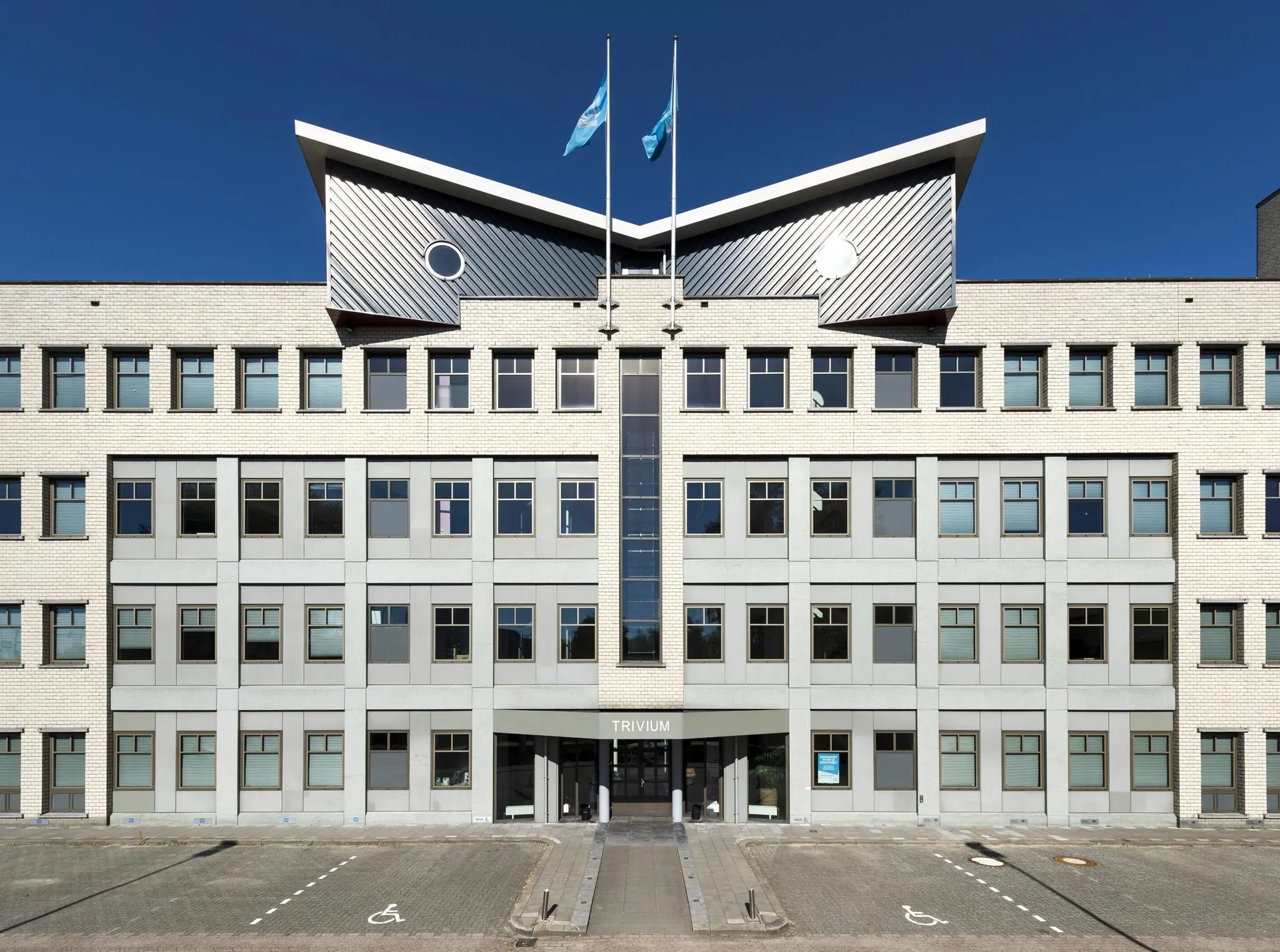 Vooraanzicht van het kantoorgebouw Trivium aan de Derkinderenstraat met symmetrische gevel en twee vlaggen op het dak.