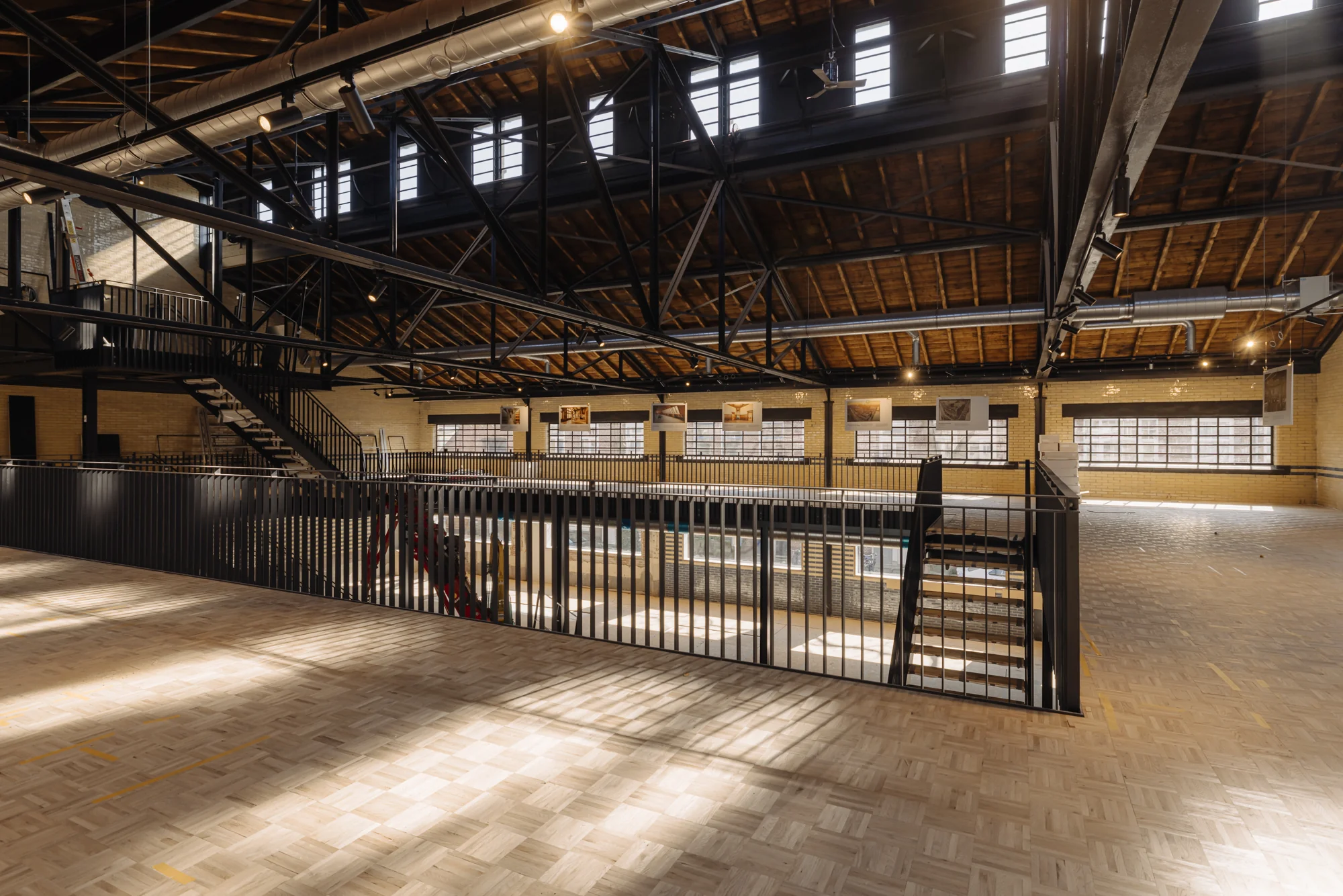 Binnenruimte van een industriële loods aan de Leidseweg met houten vloer, metalen trappen en zichtbare dakconstructie.