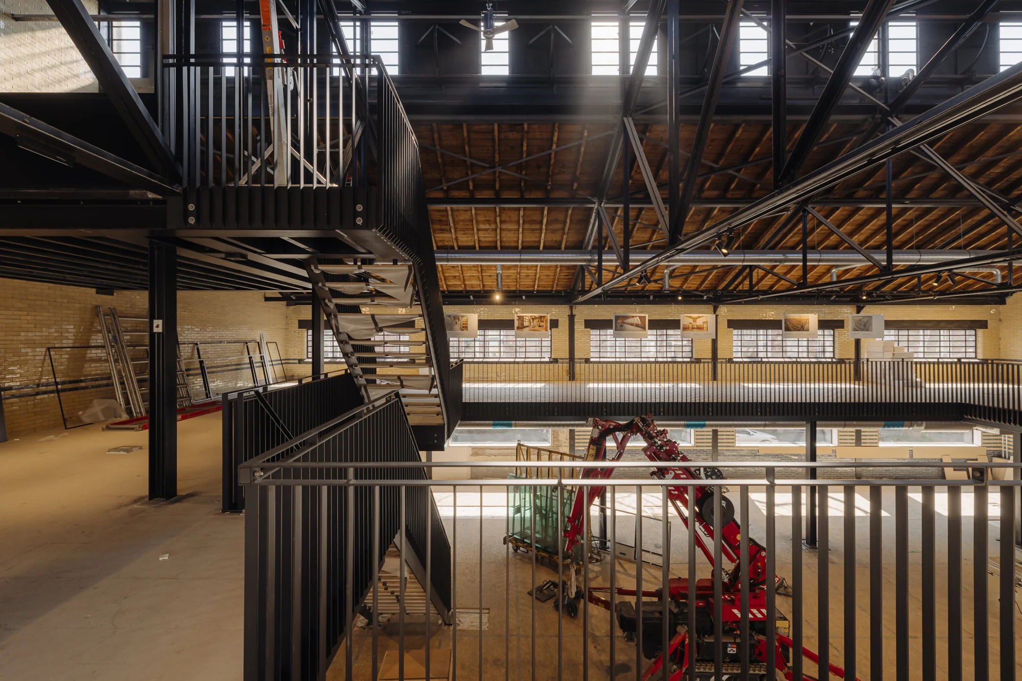 Industrieel interieur van een gerenoveerd pand aan de Leidseweg met stalen trap, houten dakconstructie en bouwmaterialen op de begane grond.