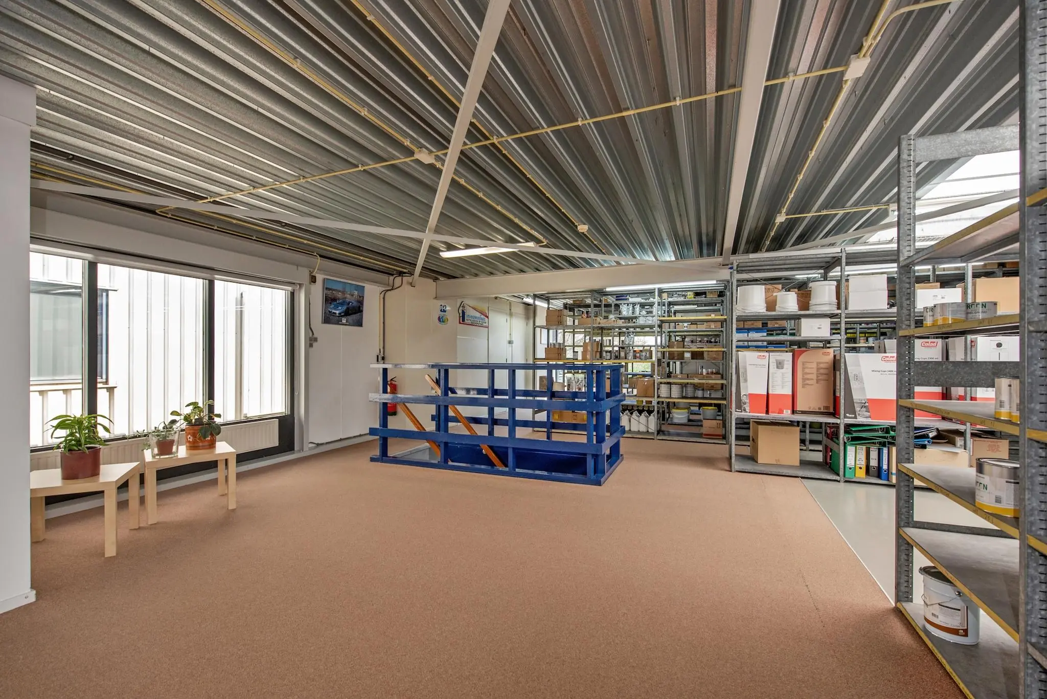 Opslagruimte met metalen schappen, kantoorbenodigdheden en een trapomheining in een pand aan de Lagosweg.