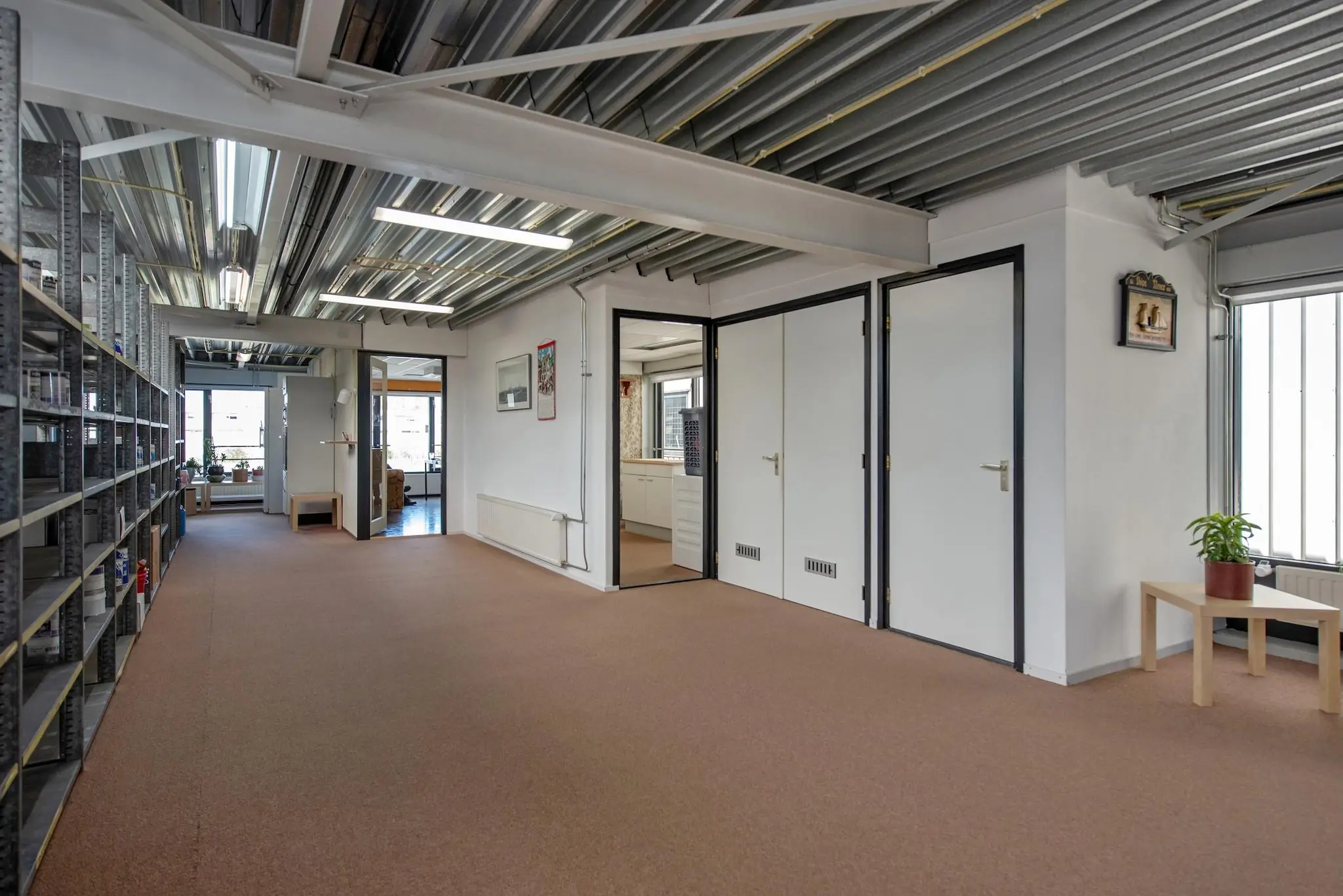 Gang in een bedrijfsruimte aan de Lagosweg met industriële uitstraling, kantoorruimtes en metalen plafondconstructie.