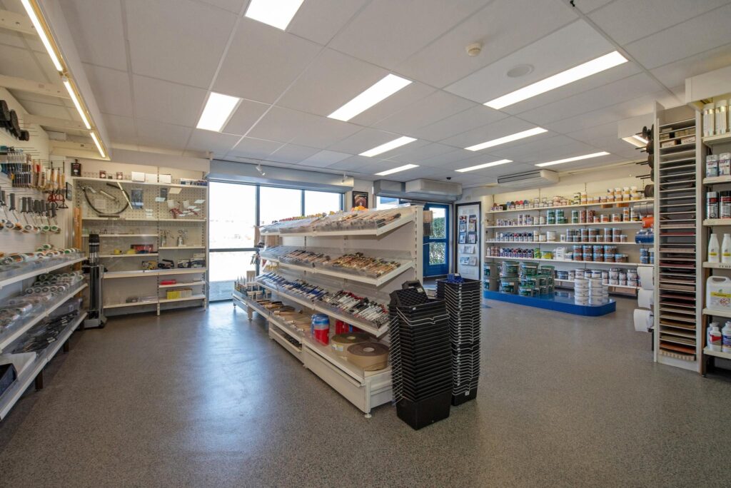 Winkelinterieur van een bouwmarkt aan de Lagosweg met schappen vol schilderbenodigdheden, verf en gereedschap.