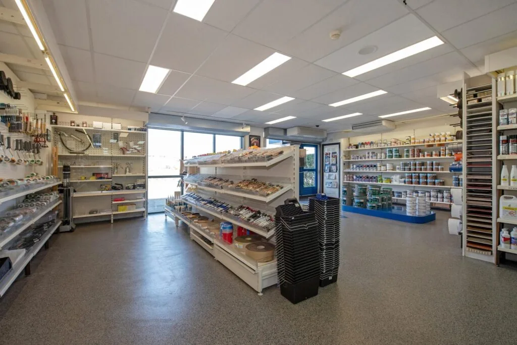 Winkelinterieur van een bouwmarkt aan de Lagosweg met schappen vol schilderbenodigdheden, verf en gereedschap.