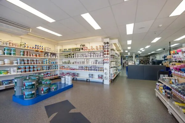 Verfwinkel met volle schappen verfblikken, schildersbenodigdheden en overzichtelijke presentatie.