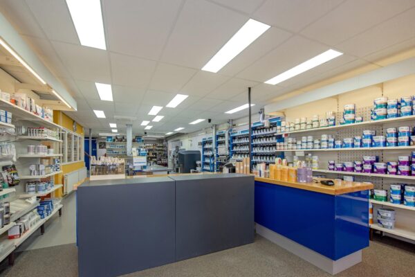Interieur van een verfwinkel aan de Lagosweg met toonbank en schappen vol verfblikken en schildersbenodigdheden.