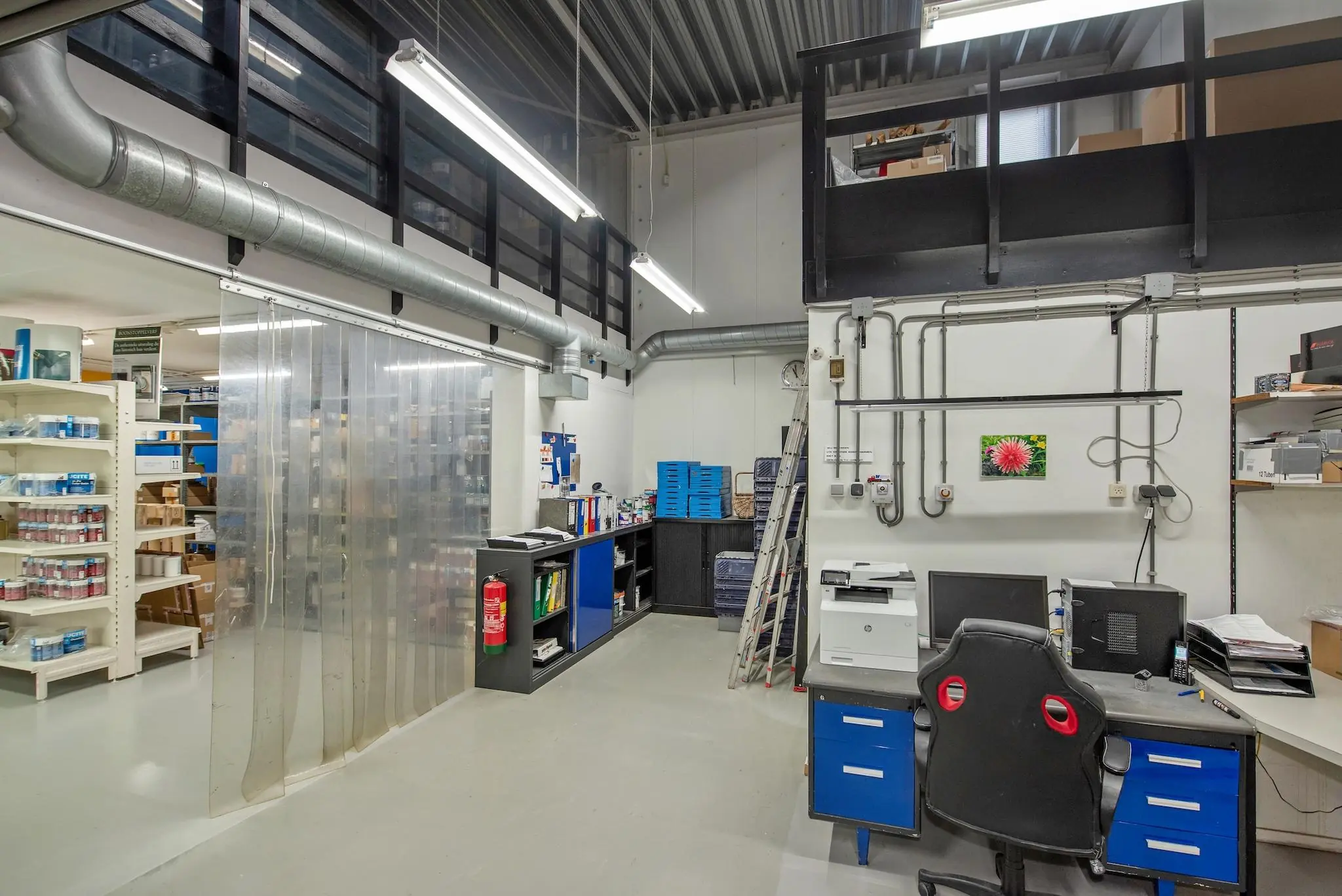 Kantoorruimte in een magazijn aan de Lagosweg met bureaus, opbergkasten, printer en industriële inrichting.