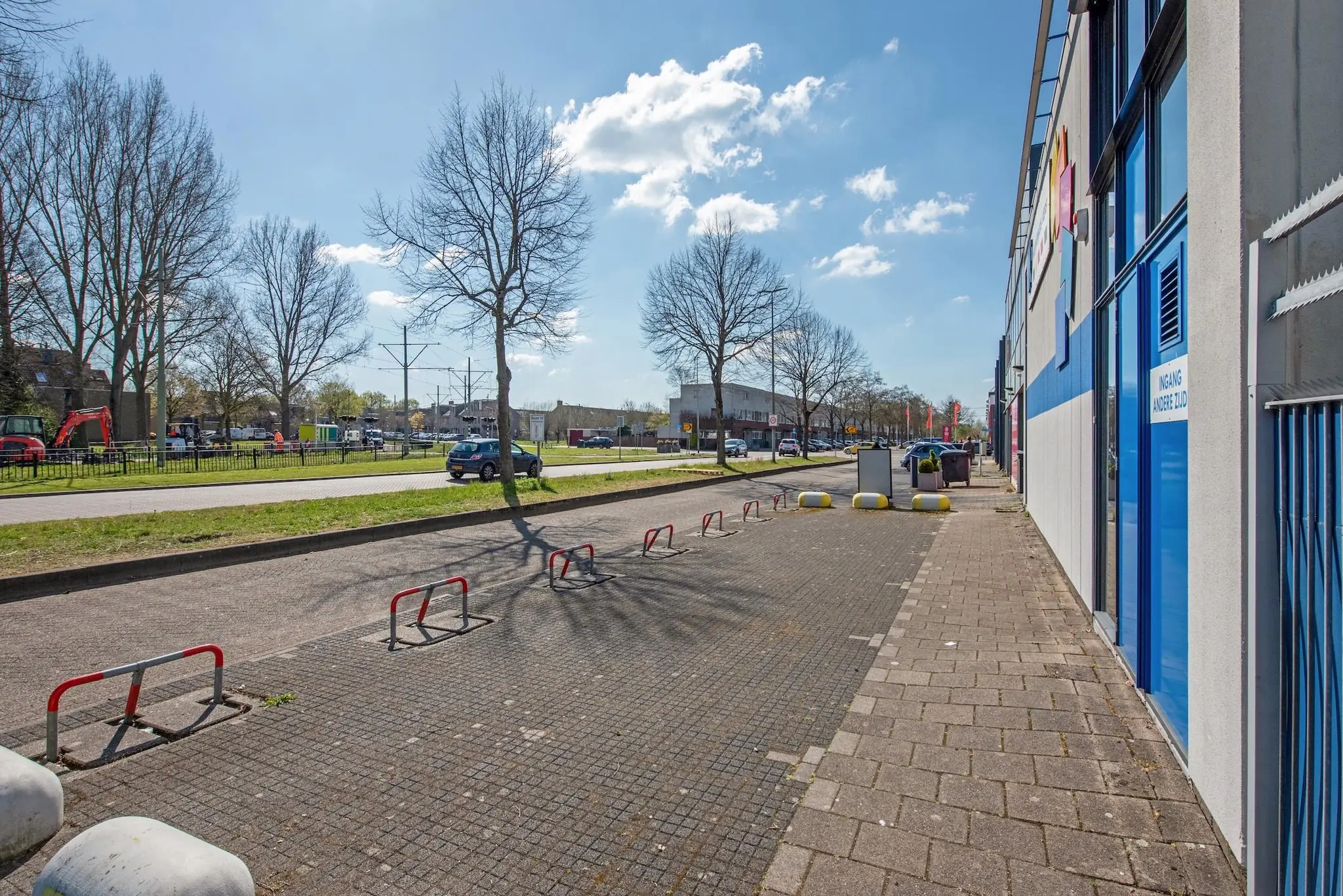 Straatbeeld van de Lagosweg met een stoep, parkeerbeugels en bedrijvenpand aan de rechterzijde op een zonnige dag.