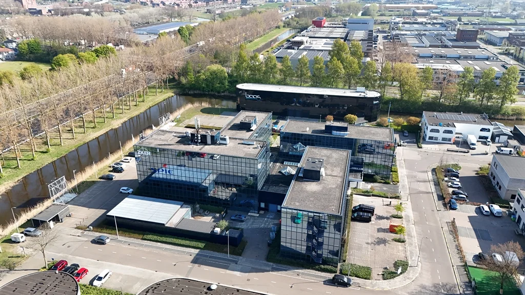 Aerial view of the modern office buildings on Essebaan in Capelle aan den IJssel, surrounded by roads, trees, and a canal.