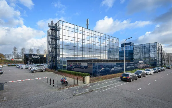 Modern glass office buildings with the company name "Baas" and a parking lot on Essebaan street.