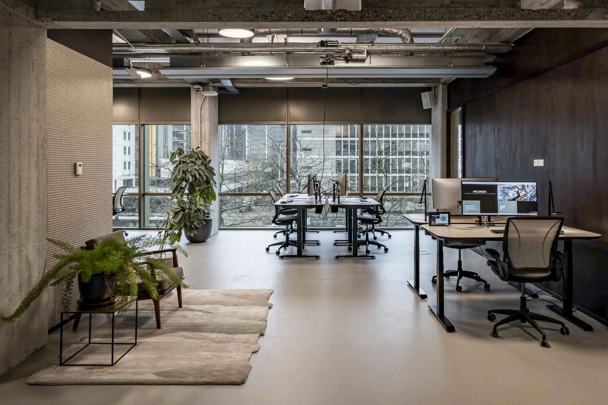 Modern kantoorinterieur in Hofplein met werkplekken, grote ramen en industriële details.
