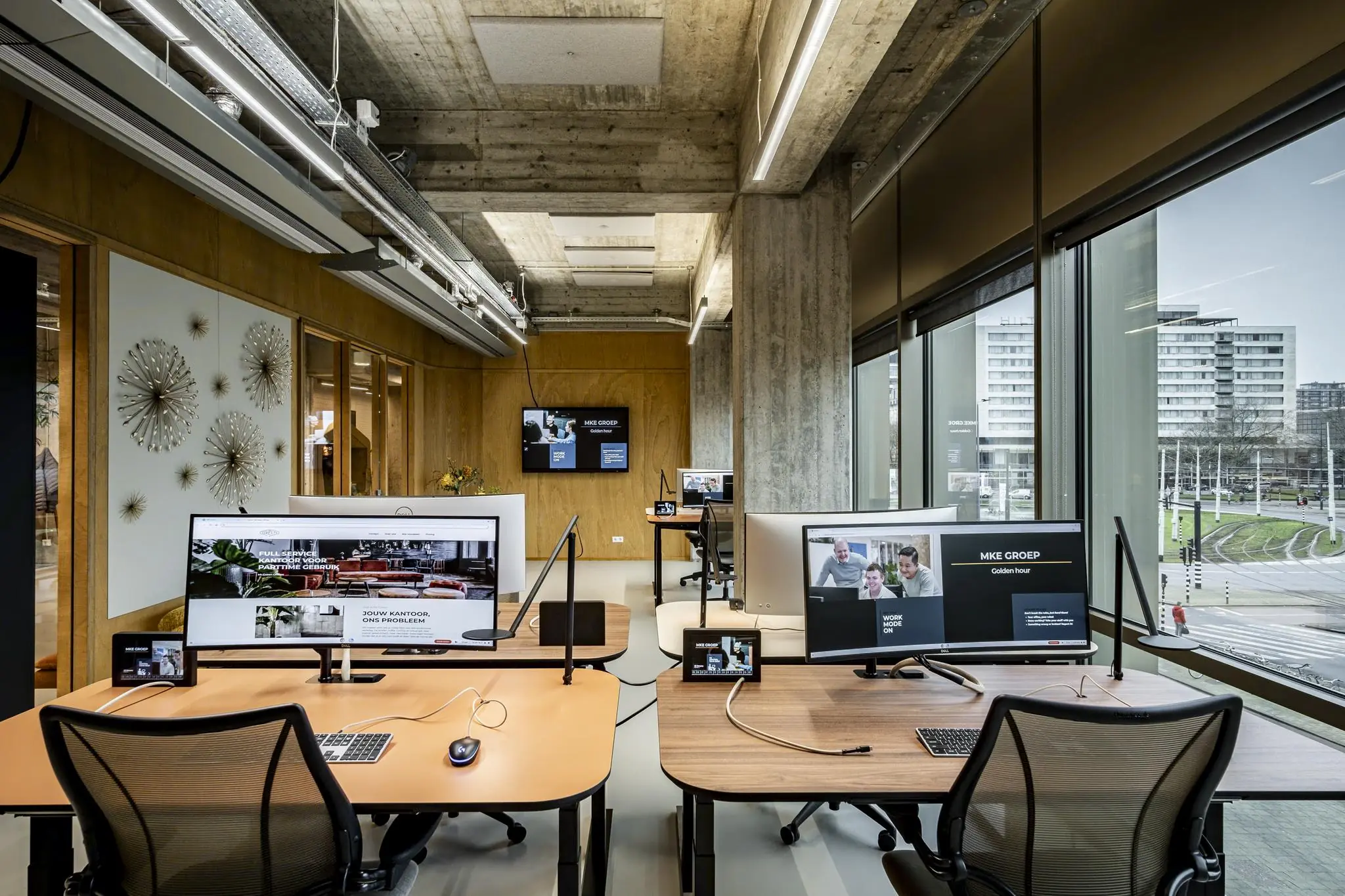 Modern kantoorinterieur aan het Hofplein met werkplekken, grote beeldschermen en uitzicht op Rotterdamse gebouwen en tramlijnen.