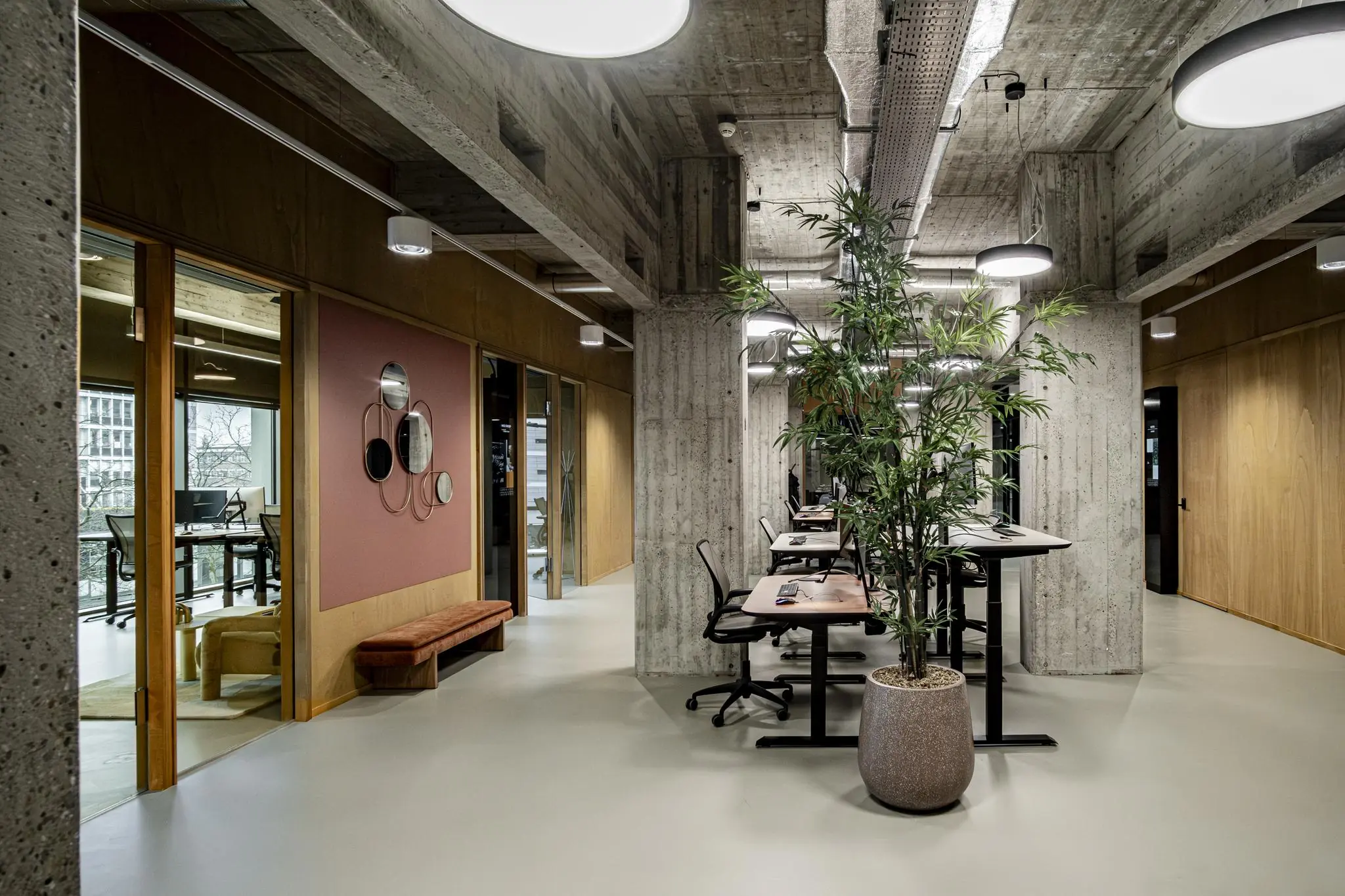Modern kantoorinterieur in Hofplein met betonnen pilaren, bureaus, vergaderruimtes en een grote kamerplant.