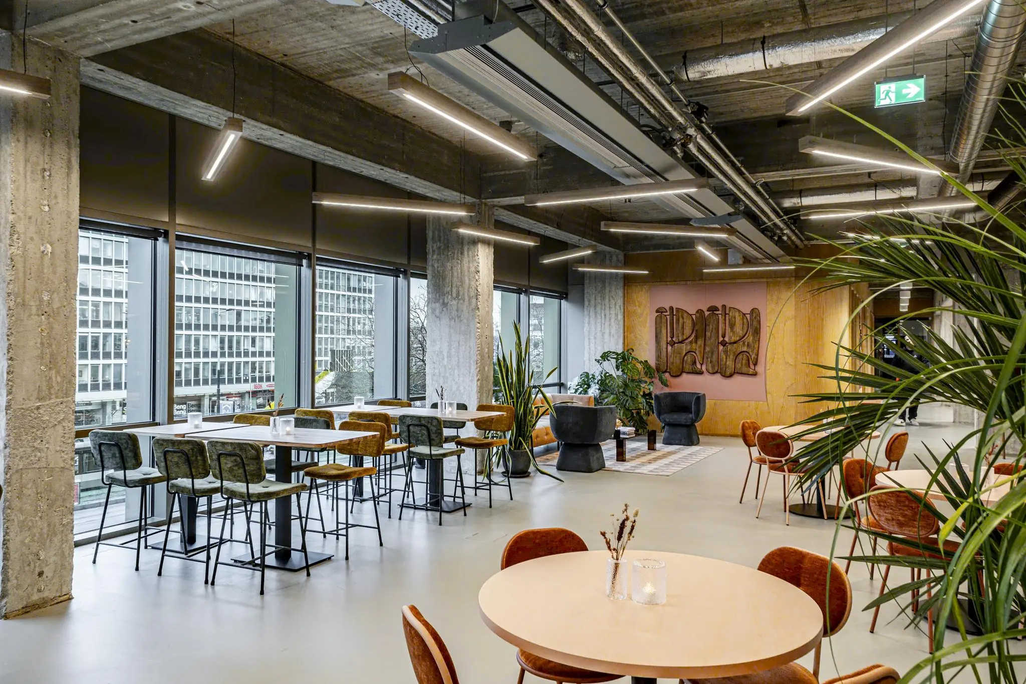 Modern ingerichte kantoorlounge aan het Hofplein met grote ramen, zitplekken en industriële elementen.
