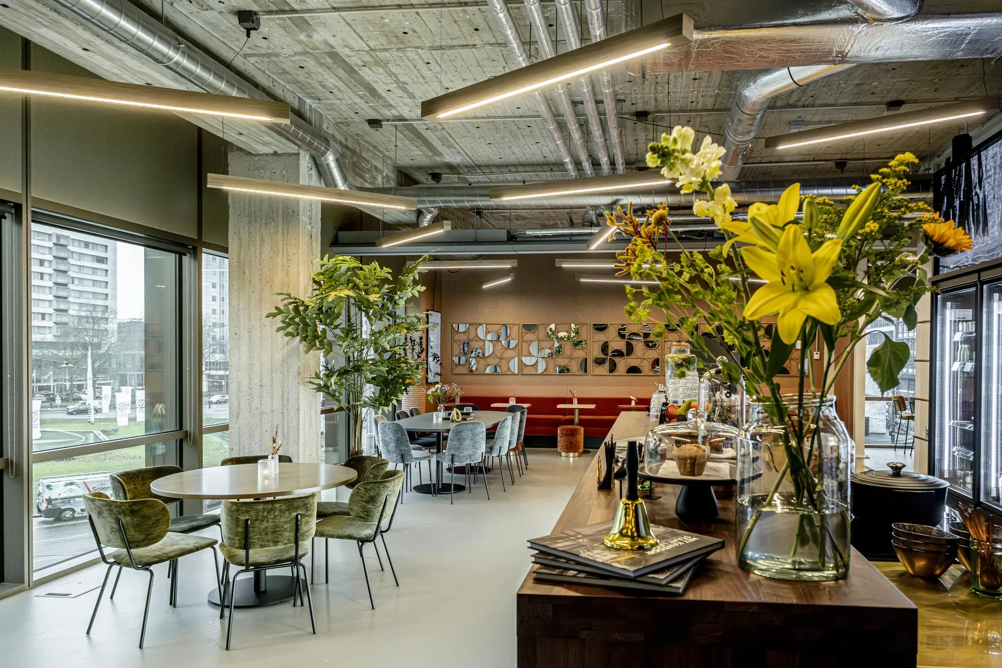 Modern ingericht horecagedeelte in Hofplein met bloemen op de voorgrond en uitzicht op de stad.