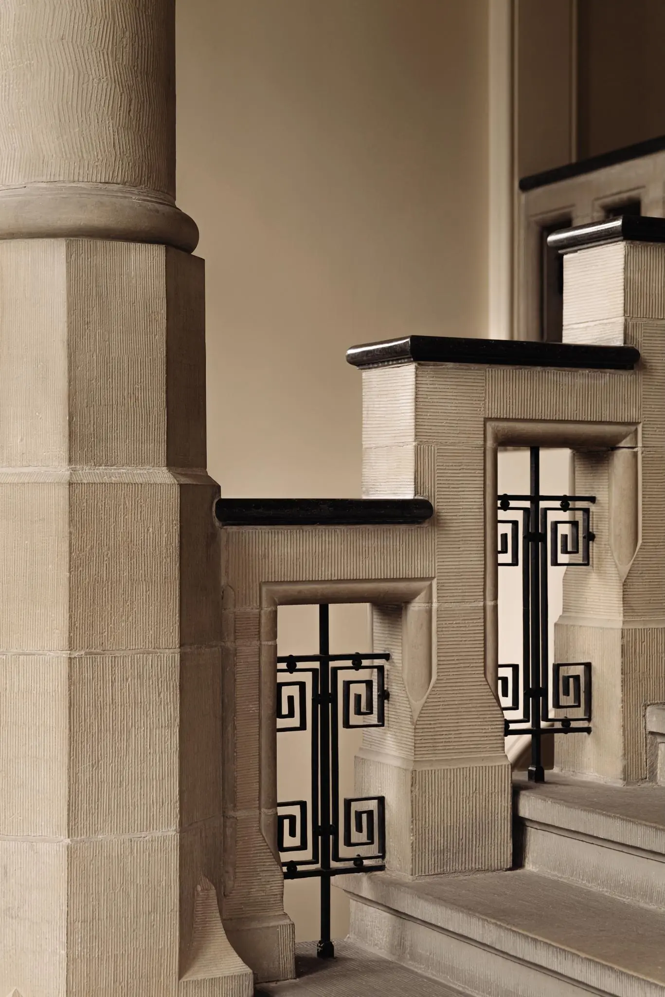 Detail van een monumentaal trappenhuis aan de Leidseweg met natuurstenen balustrade en zwart smeedijzeren hekwerk in geometrisch patroon.