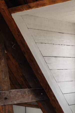 Detail van een houten dakconstructie aan de Leidseweg met wit geschilderde planken en verweerd donkerhout.