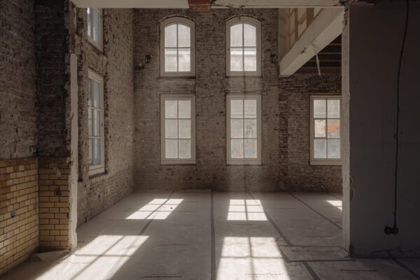 Lichte, lege ruimte aan de Leidseweg met bakstenen muren, hoge ramen en zichtbare renovatiewerkzaamheden.