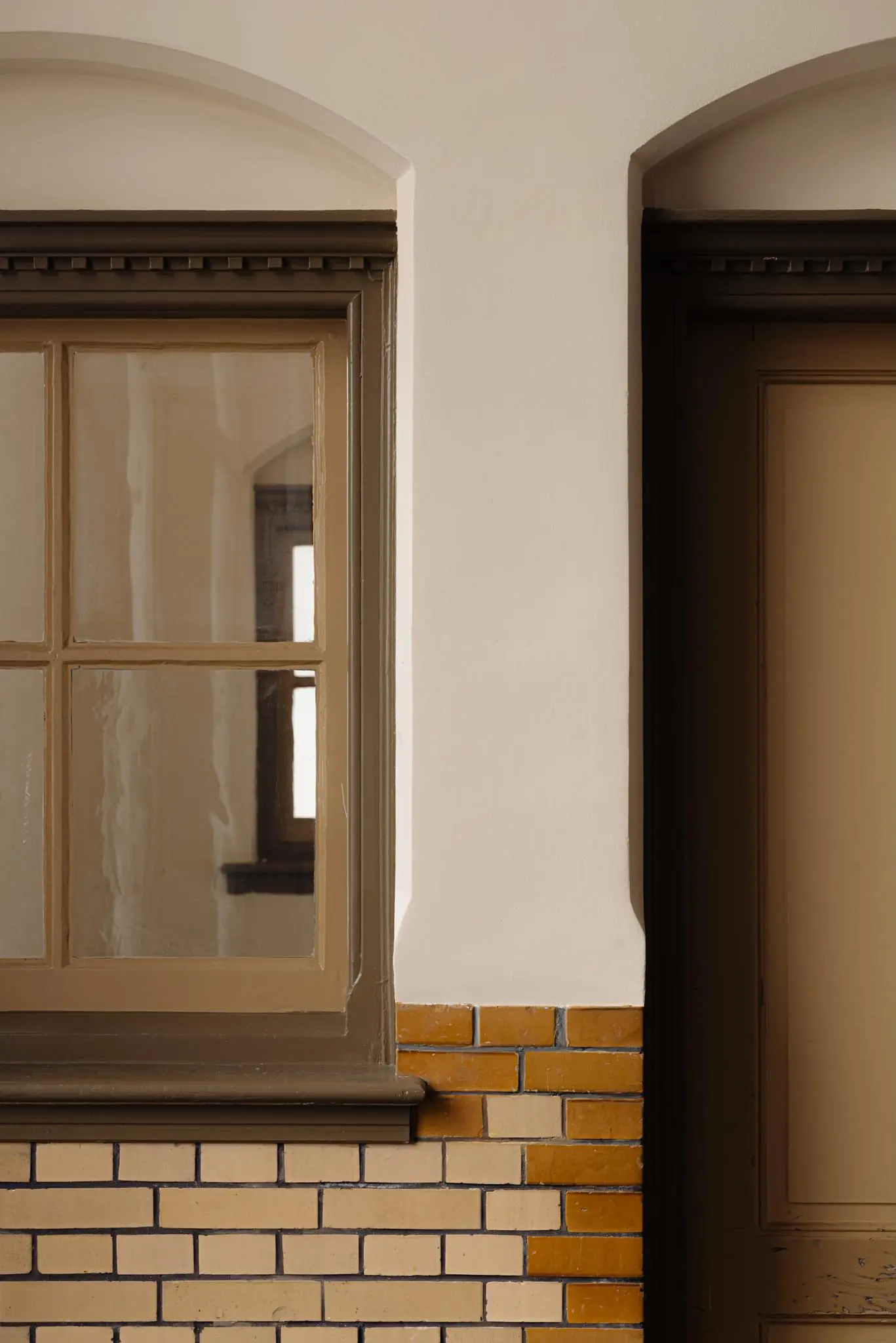 Detail van een gevel aan de Leidseweg met een raampartij, deur en geelbruine bakstenen muur.