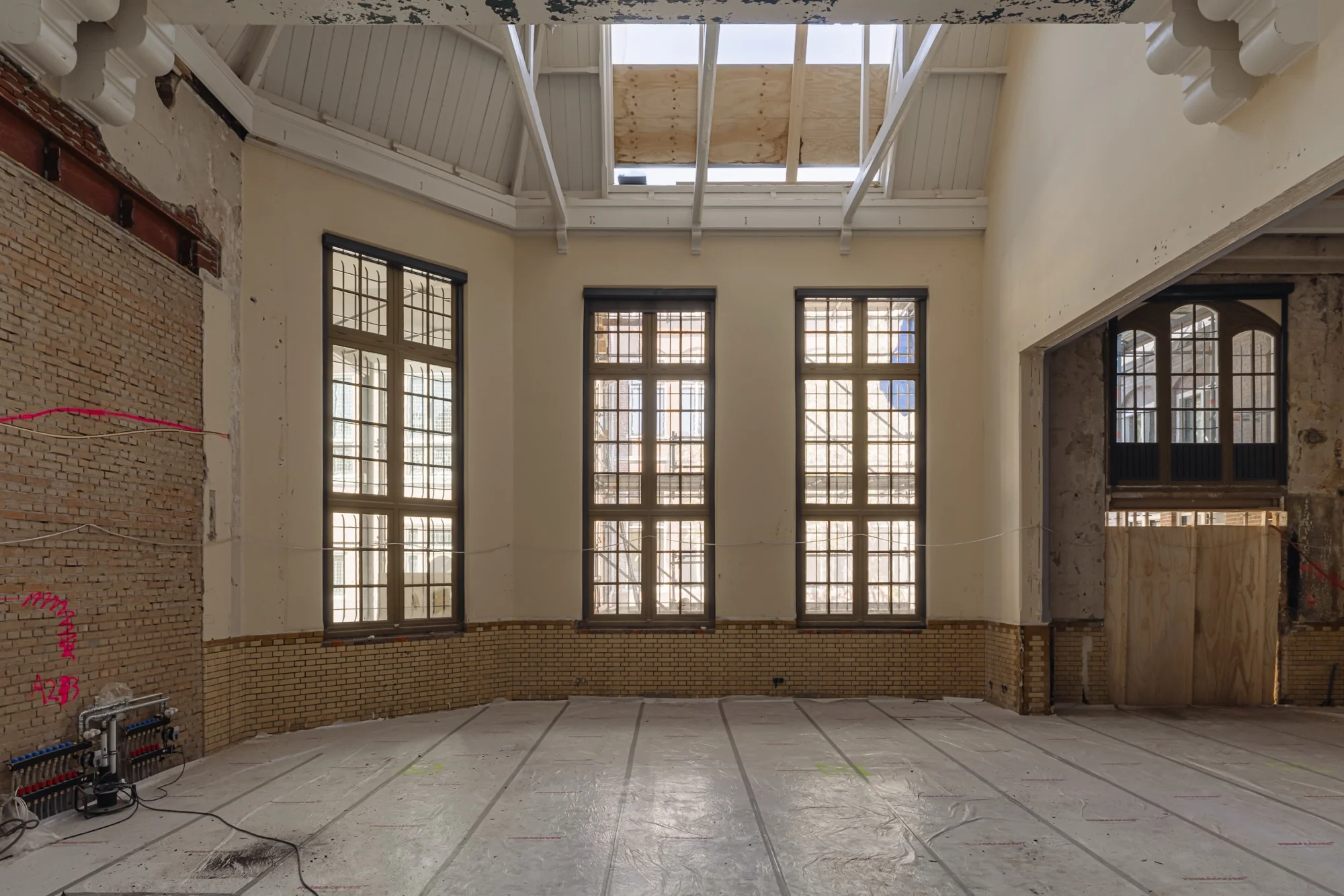 Een grote, hoge ruimte aan de Leidseweg met karakteristieke ramen, gele bakstenen en zicht op renovatiewerkzaamheden.