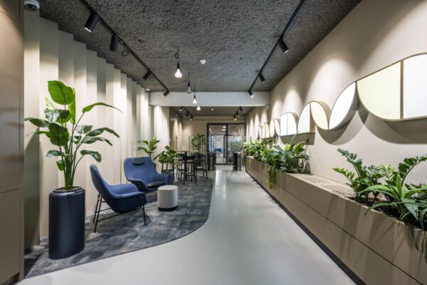 Moderne kantoorlounge aan de Singel met designmeubilair, veel planten en sfeervolle verlichting.