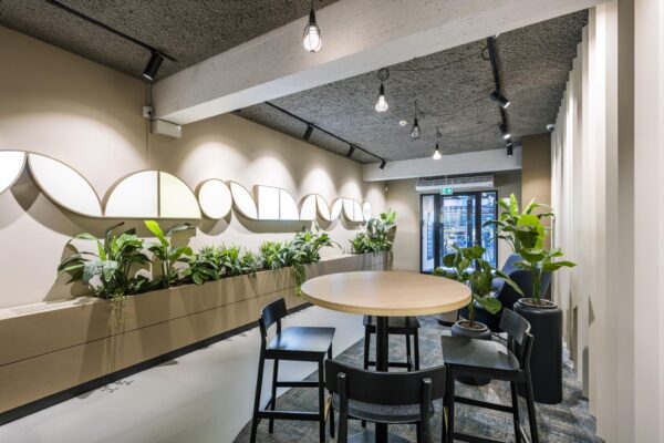 Moderne wachtruimte met ronde tafel, zwarte stoelen, veel groene planten en wanddecoratie in het gebouw aan de Singel.