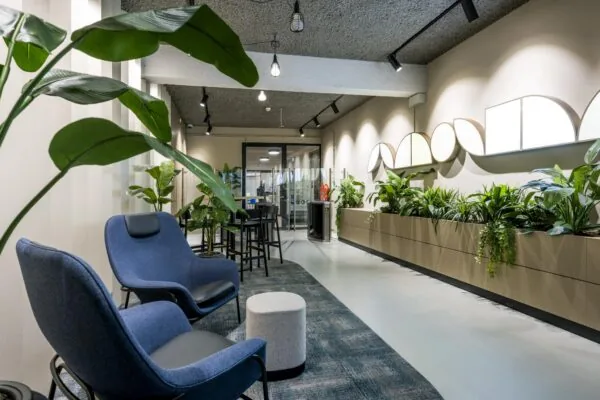 Moderne wachtruimte met comfortabele blauwe stoelen, veel groenplanten en decoratieve wandverlichting in het pand aan de Singel.