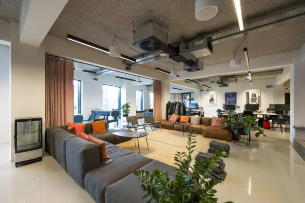 Modern kantoorinterieur met grote zithoek, werkplekken, planten en een speels ingerichte gemeenschappelijke ruimte aan de Singel.