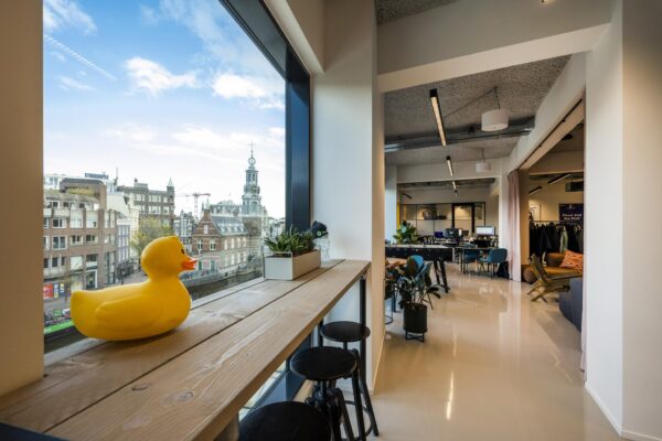 Modern kantoorinterieur met uitzicht op de Singel in Amsterdam en een gele rubberen eend op de vensterbank.