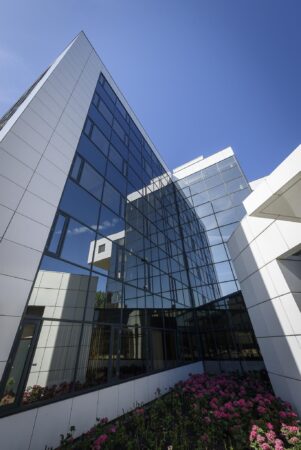 Modern kantoorgebouw aan de Cypresbaan met glazen gevel en bloemperk op de voorgrond.