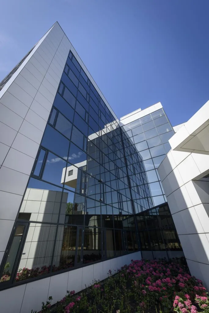 Modern kantoorgebouw aan de Cypresbaan met glazen gevel en bloemperk op de voorgrond.