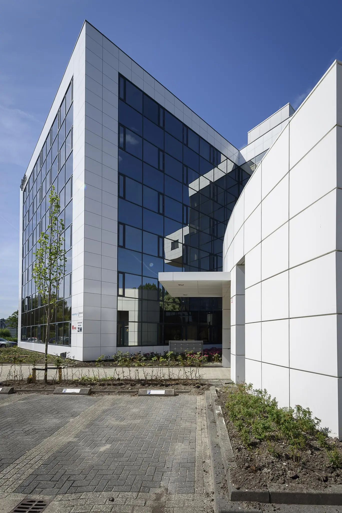 Modern kantoorgebouw aan de Cypresbaan met witte gevelpanelen en spiegelende ramen.