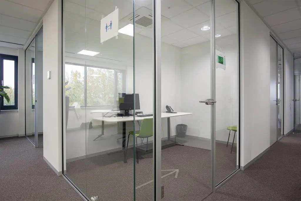 Kantoorruimte met glazen wanden aan de Cypresbaan, ingericht met bureaus, stoelen en computers.