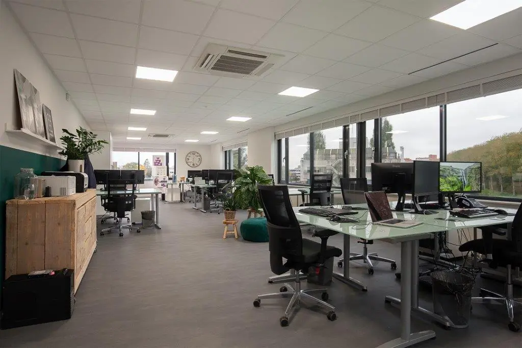 Modern kantoorinterieur aan de Cypresbaan met glazen bureaus, ergonomische stoelen en grote ramen met uitzicht op groen.