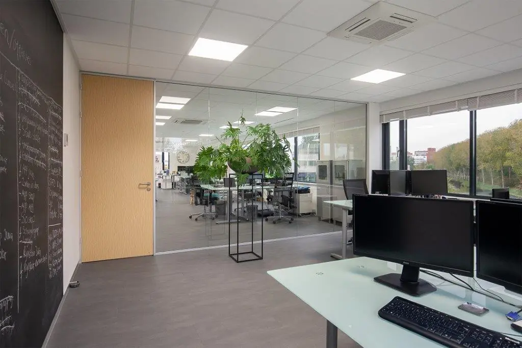 Moderne kantoorruimte aan de Cypresbaan met glazen wanden, werkplekken en uitzicht op groen.