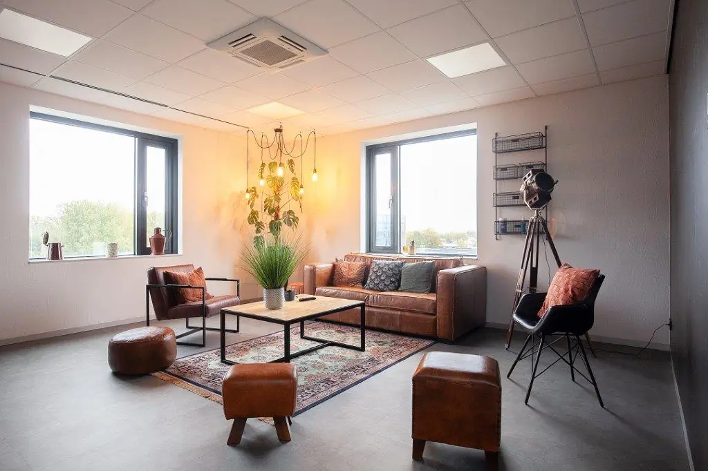 Sfeervol ingerichte wachtruimte met leren banken, vintage decor en grote ramen aan de Cypresbaan.