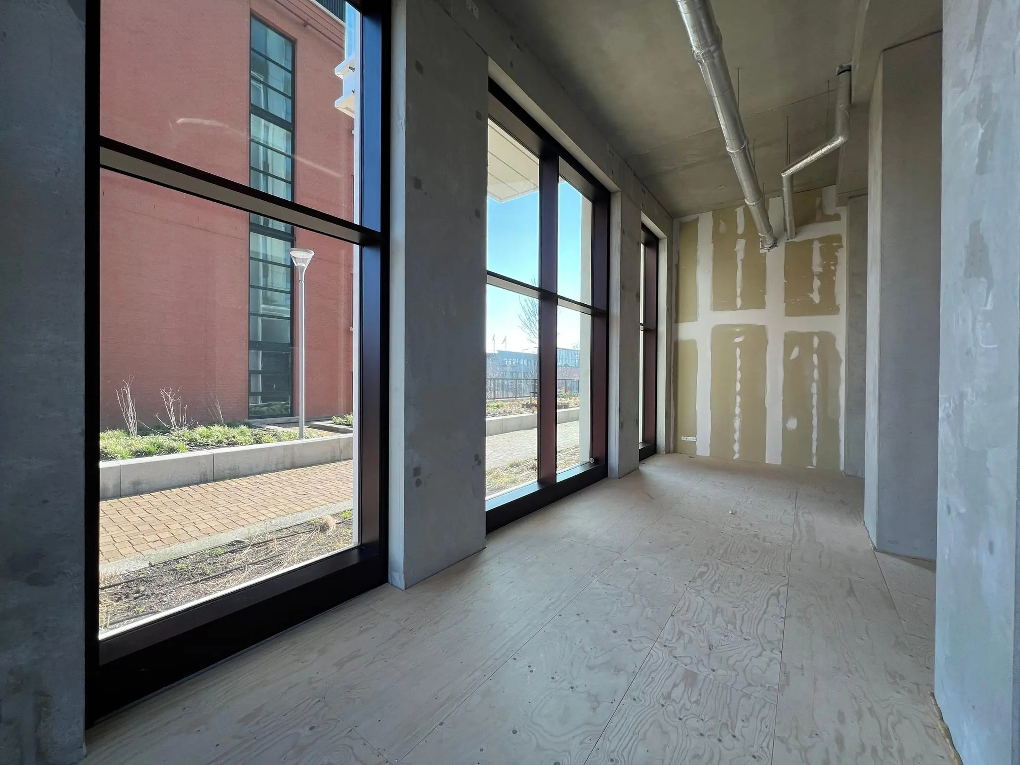 Leegstaand casco winkelpand aan het Maanplein met grote ramen en zicht op de straat.