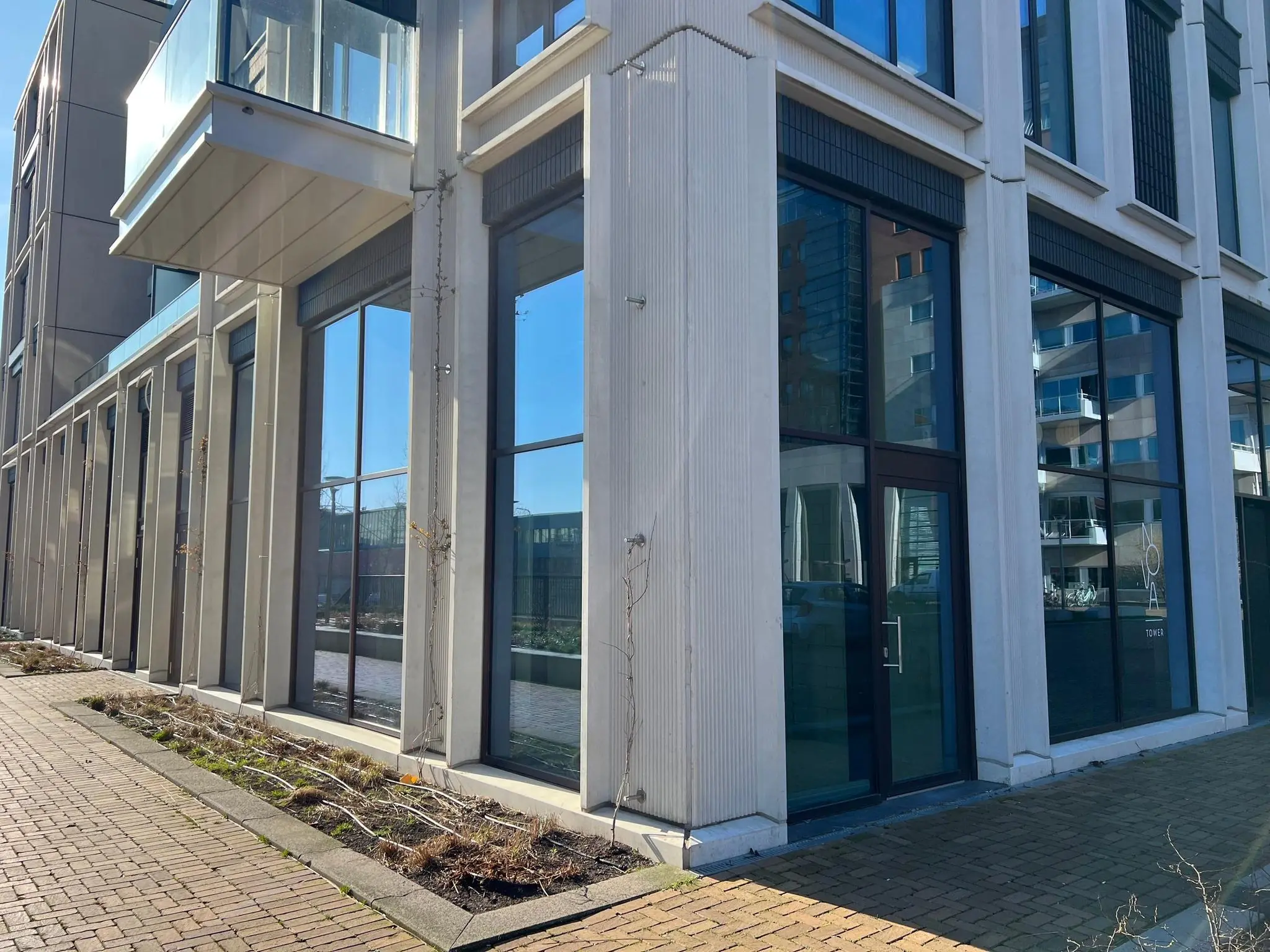 Moderne gevel van een kantoorpand aan het Maanplein met grote ramen en een glazen balkon.