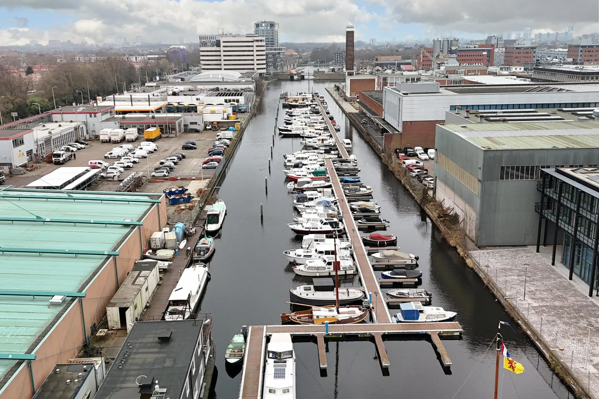 Luchtfoto van jachthaven aan het Maanplein met aangrenzende industriële gebouwen en geparkeerde voertuigen.