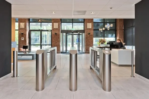 Moderne entreehal met tourniquetpoortjes, een receptiebalie en glazen draaideur aan de Prof. W.H. Keesomlaan.
