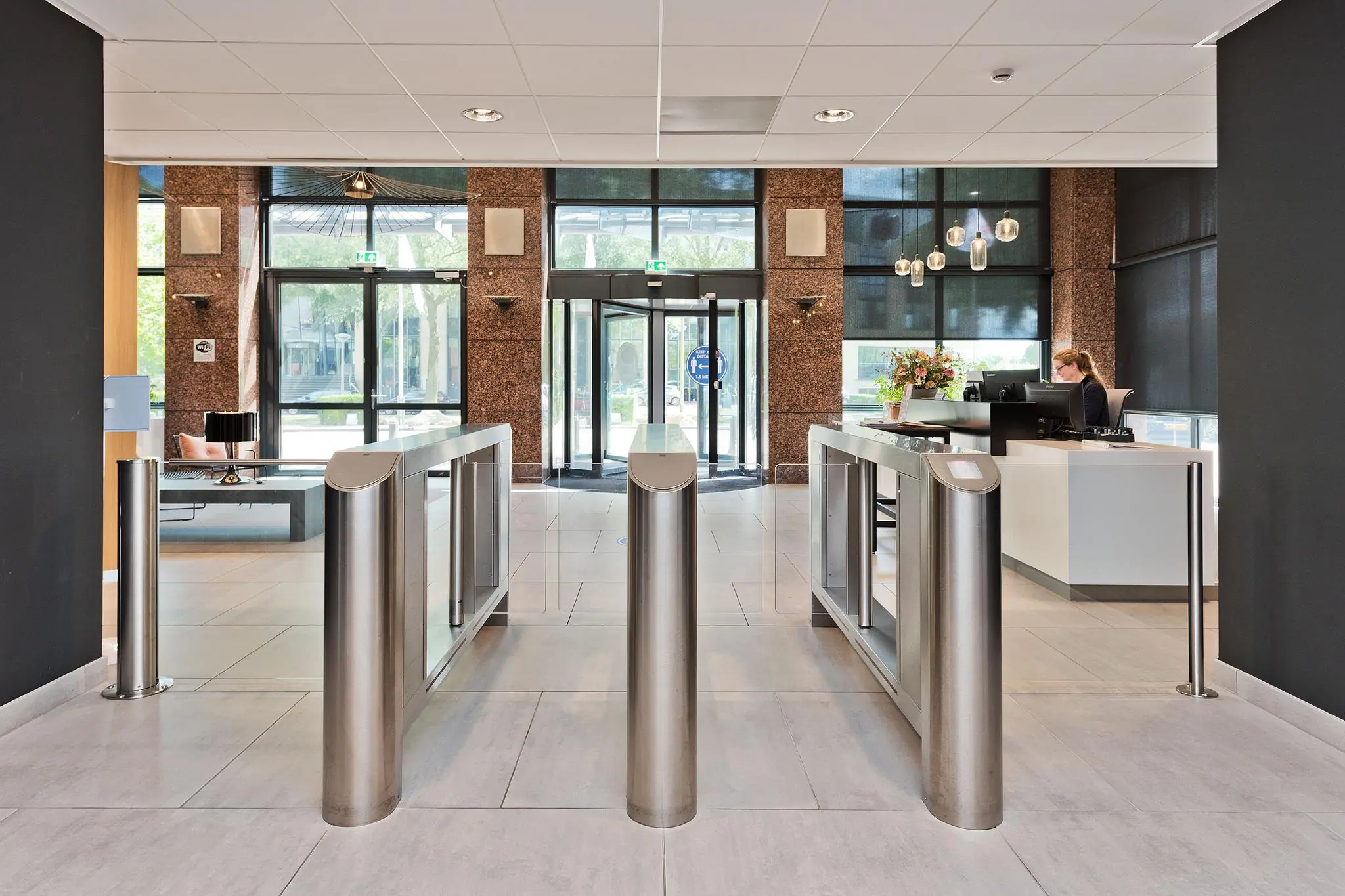 Moderne entreehal met tourniquetpoortjes, een receptiebalie en glazen draaideur aan de Prof. W.H. Keesomlaan.